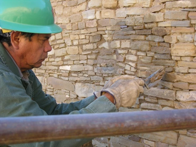 National Park Service employee Harold Suina carefully repointing the joints in an existing stone wall.
